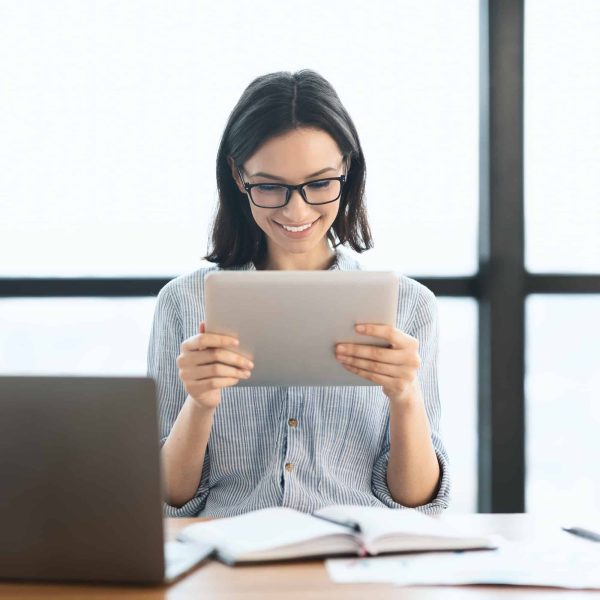 young-girl-holding-tablet-and-using-laptop-at-office.jpg